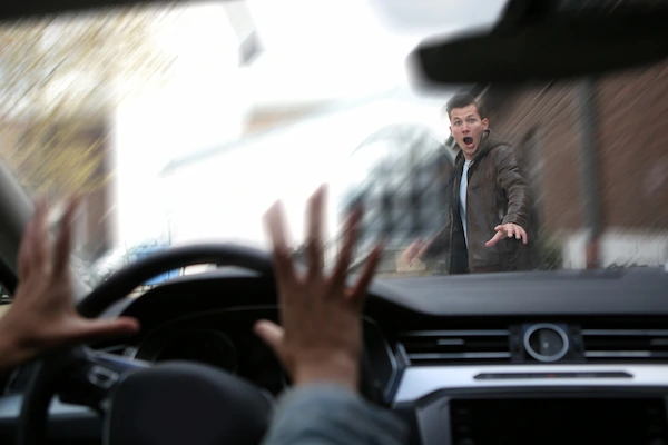 A vehicle and a pedestrian crossing the street symbolize a case for a pedestrian accident lawyer to review.