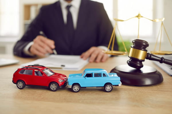 A car accident lawyer works on a case at a desk with model cars.